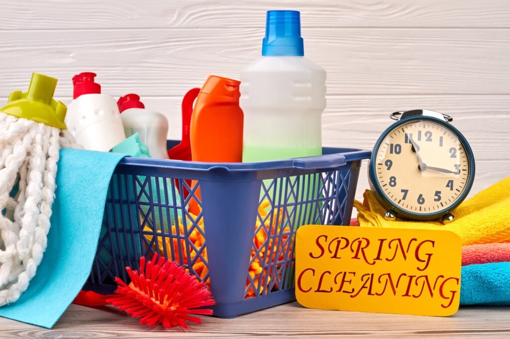 Basket with cleaning items on wooden background.