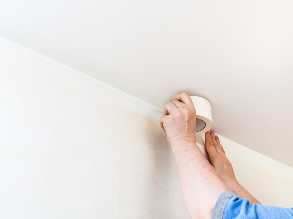 Decorator fixes tape on wall before painting